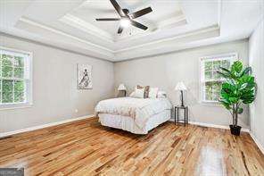 bedroom with hardwood / wood-style floors, ceiling fan, and multiple windows