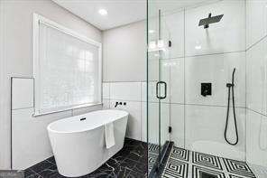 bathroom featuring independent shower and bath and tile walls