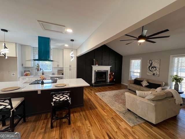 kitchen featuring wall chimney exhaust hood, dark hardwood / wood-style flooring, white cabinetry, and hanging light fixtures