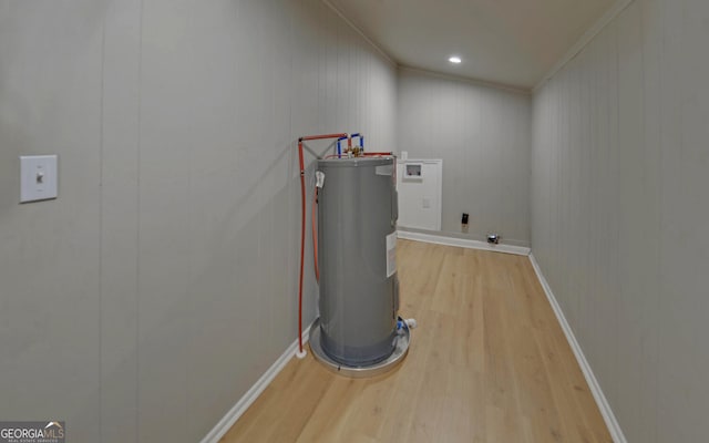 clothes washing area with hookup for an electric dryer, hookup for a washing machine, light wood-type flooring, crown molding, and water heater