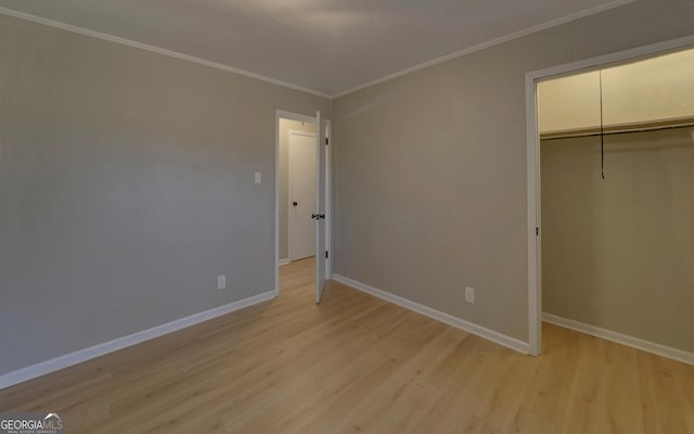 unfurnished bedroom featuring light wood-type flooring, crown molding, and a closet