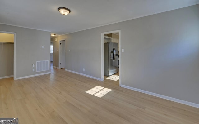 empty room featuring light hardwood / wood-style flooring and ornamental molding