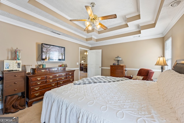 bedroom with ornamental molding, light colored carpet, ceiling fan, and a tray ceiling