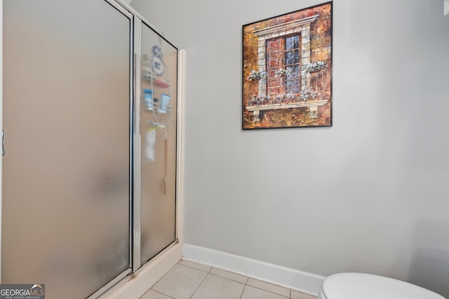 bathroom with tile patterned flooring, toilet, and a shower with shower door