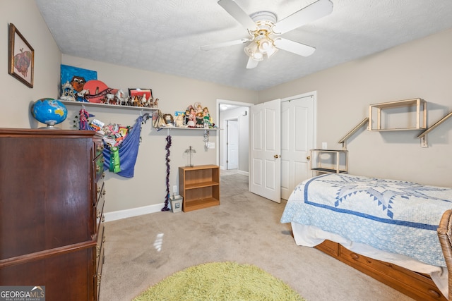 carpeted bedroom with ceiling fan, a closet, and a textured ceiling