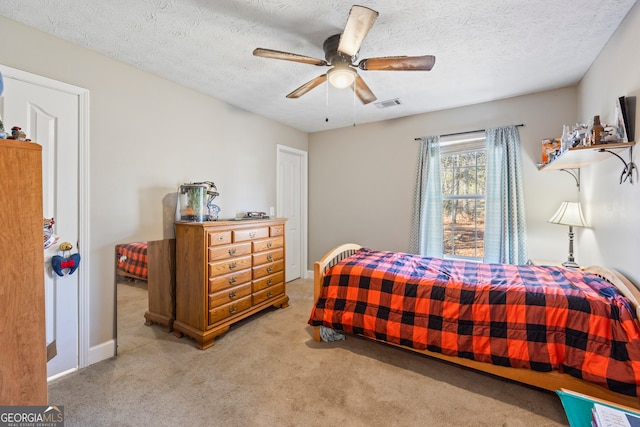 bedroom with ceiling fan, carpet floors, and a textured ceiling