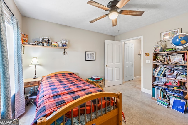 carpeted bedroom featuring ceiling fan and a textured ceiling