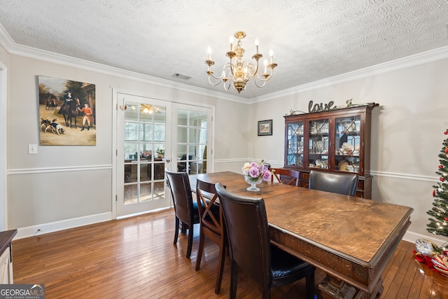 dining area with crown molding, hardwood / wood-style floors, a textured ceiling, and a chandelier