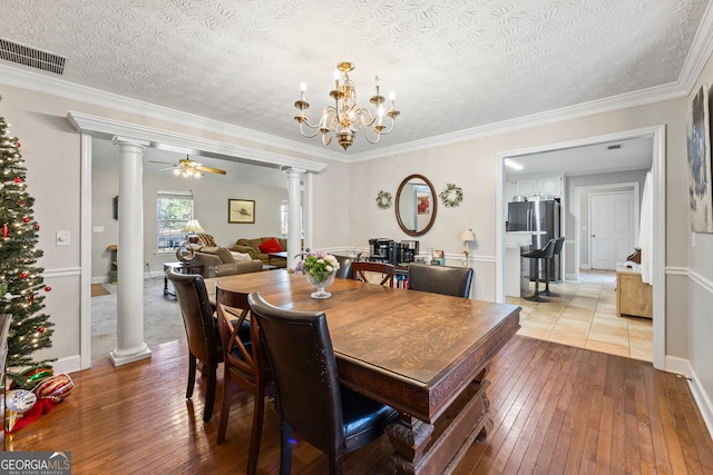 dining space featuring ornamental molding, ceiling fan with notable chandelier, light hardwood / wood-style flooring, and ornate columns