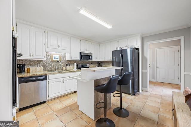 kitchen featuring light tile patterned flooring, sink, white cabinetry, appliances with stainless steel finishes, and a kitchen island