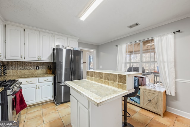 kitchen with appliances with stainless steel finishes, a kitchen breakfast bar, white cabinets, a kitchen island, and decorative backsplash