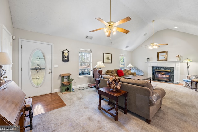 carpeted living room featuring ceiling fan, lofted ceiling, a fireplace, and a textured ceiling