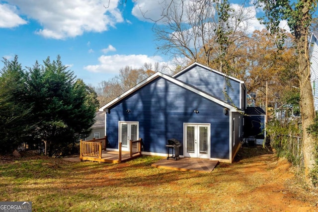 back of house featuring a lawn, a wooden deck, and french doors