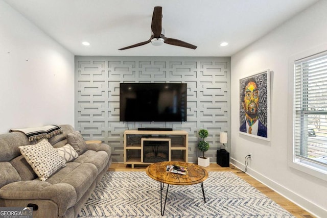 living room with light hardwood / wood-style floors, ceiling fan, and a healthy amount of sunlight