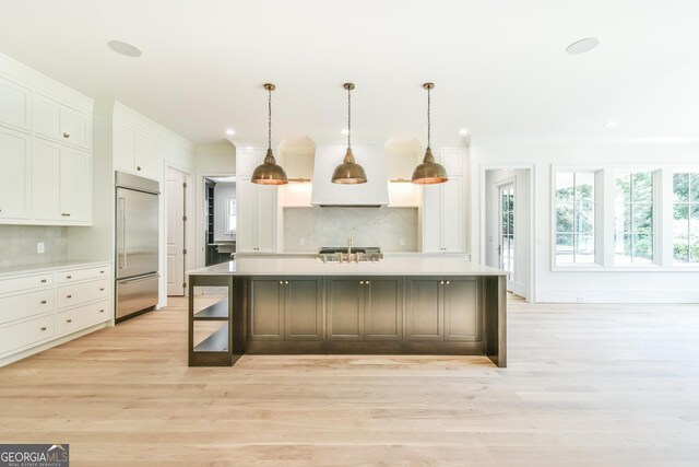 kitchen with stainless steel built in fridge, pendant lighting, a kitchen island with sink, and decorative backsplash