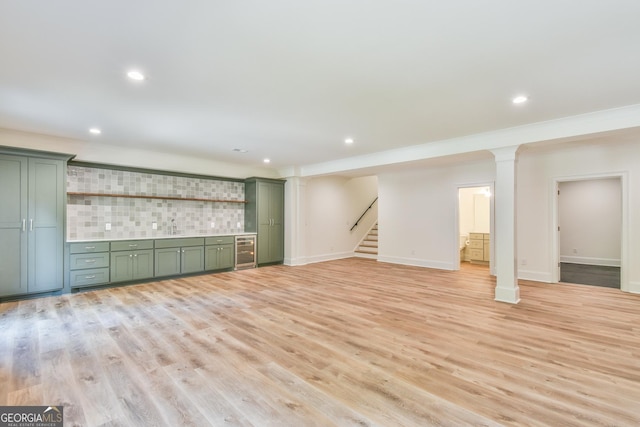 unfurnished living room with ornamental molding, light wood-type flooring, wine cooler, and sink