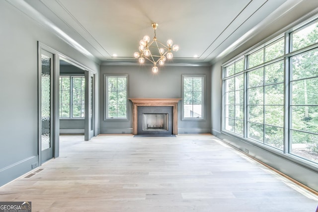 unfurnished living room featuring a notable chandelier, light hardwood / wood-style flooring, and ornamental molding