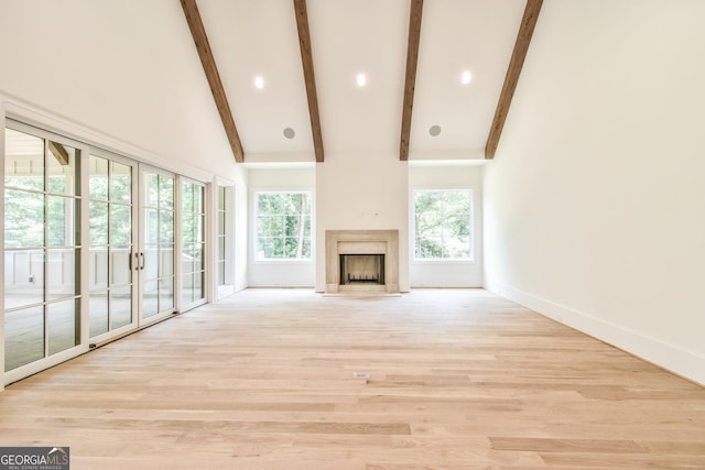 unfurnished living room featuring a fireplace, high vaulted ceiling, light hardwood / wood-style floors, and beamed ceiling