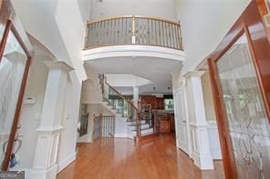 foyer featuring hardwood / wood-style flooring, a towering ceiling, and decorative columns