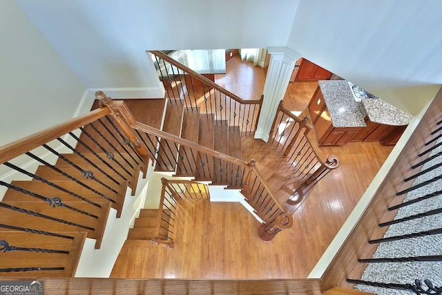 staircase with decorative columns and hardwood / wood-style floors