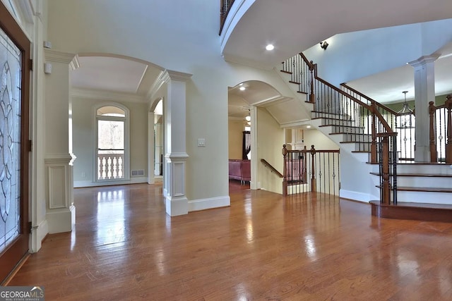 foyer entrance with crown molding, hardwood / wood-style flooring, and decorative columns