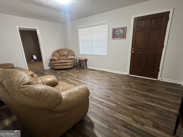 living room featuring dark wood-type flooring and a textured ceiling