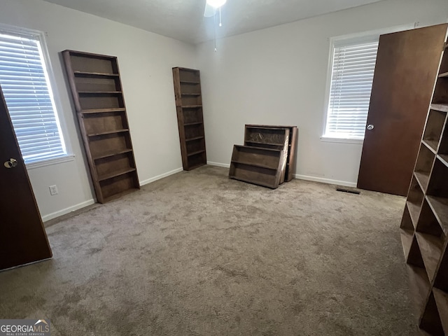 miscellaneous room with ceiling fan, a wealth of natural light, and light colored carpet