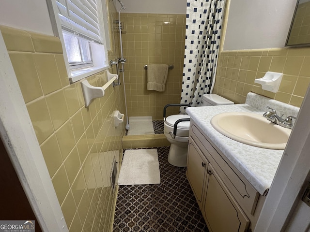 bathroom with toilet, vanity, tile walls, tile patterned flooring, and a tile shower