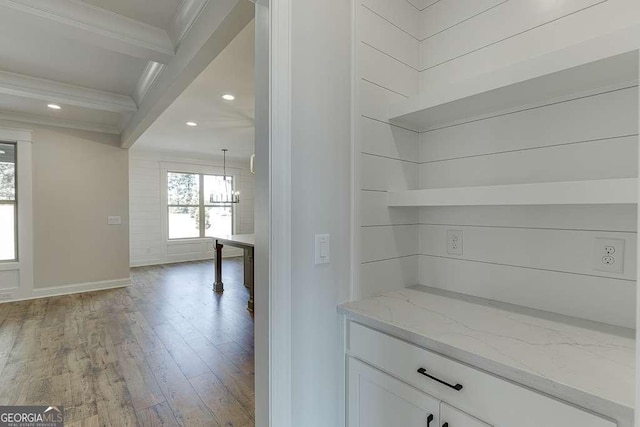 bar with light wood-type flooring, ornamental molding, beamed ceiling, light stone counters, and white cabinetry