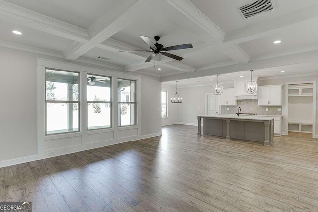 unfurnished living room with hardwood / wood-style flooring, ceiling fan with notable chandelier, beam ceiling, and coffered ceiling