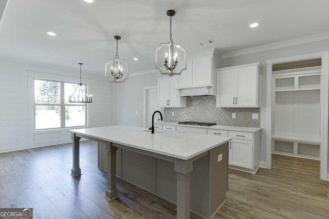 kitchen featuring white cabinets, stainless steel gas stovetop, sink, and a kitchen island with sink