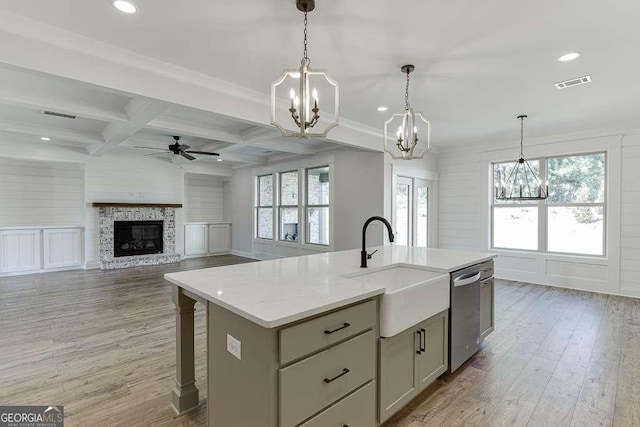 kitchen with stainless steel dishwasher, coffered ceiling, sink, beamed ceiling, and an island with sink