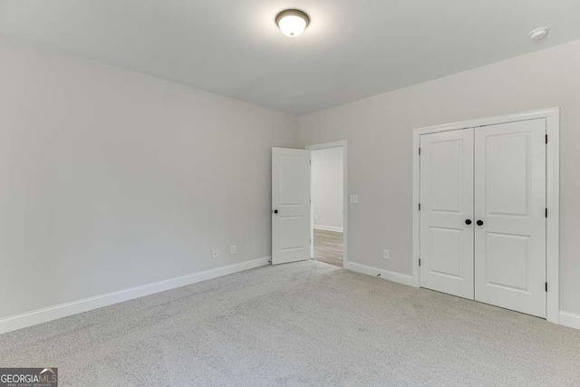 unfurnished bedroom featuring a closet and light colored carpet