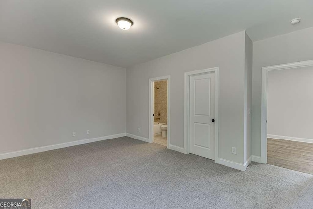 unfurnished bedroom with ensuite bathroom, a closet, and light carpet