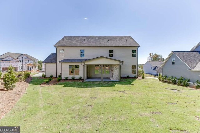 rear view of property featuring a lawn and a patio