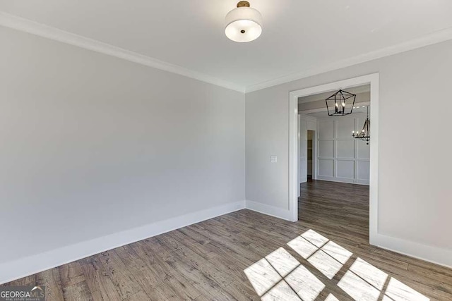 unfurnished room with hardwood / wood-style flooring, ornamental molding, and an inviting chandelier