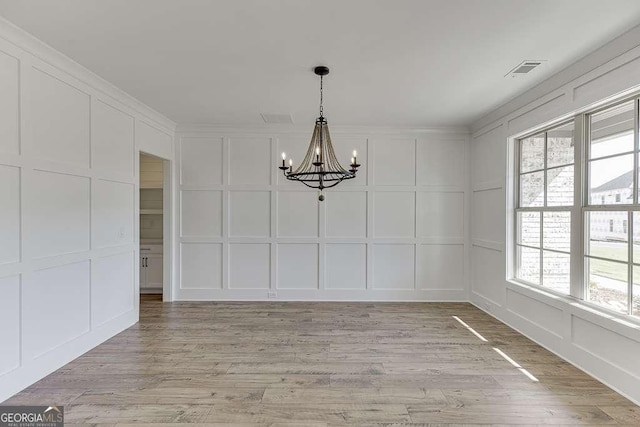 unfurnished dining area with light wood-type flooring, a wealth of natural light, and a chandelier