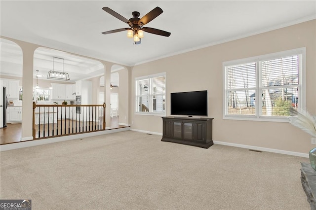 unfurnished living room featuring crown molding, ceiling fan, and light colored carpet