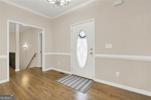 entryway featuring crown molding, wood-type flooring, and a notable chandelier