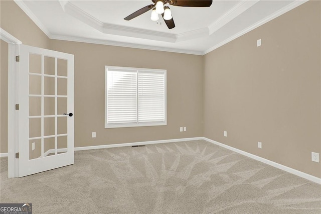 carpeted empty room featuring a tray ceiling, ceiling fan, and crown molding