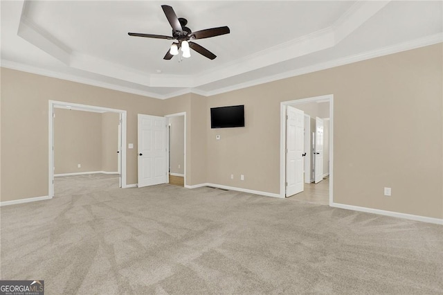 interior space featuring ceiling fan, a raised ceiling, crown molding, and light carpet