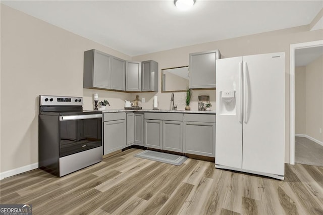 kitchen with gray cabinetry, sink, white refrigerator with ice dispenser, stainless steel electric range, and light wood-type flooring