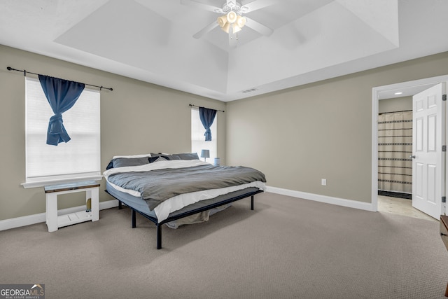 carpeted bedroom featuring multiple windows, a tray ceiling, and ceiling fan