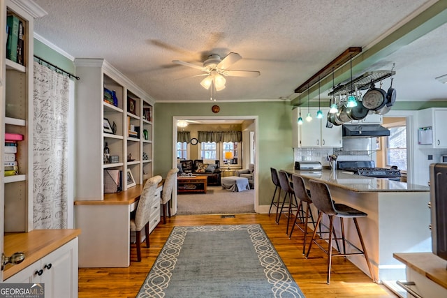 kitchen with white cabinets, range, and a kitchen breakfast bar