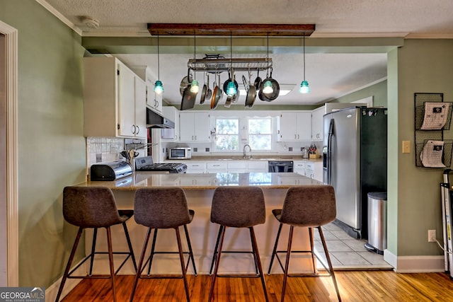 kitchen featuring white cabinetry, dishwasher, stainless steel fridge, decorative light fixtures, and range