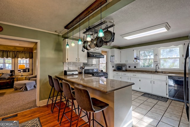 kitchen featuring white cabinets, sink, gas range, black dishwasher, and kitchen peninsula