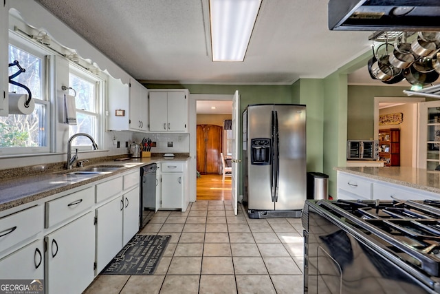 kitchen with dishwasher, white cabinets, stainless steel fridge, light tile patterned floors, and gas stove