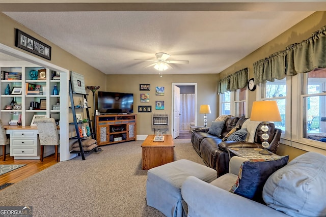 carpeted living room with a textured ceiling, heating unit, and ceiling fan