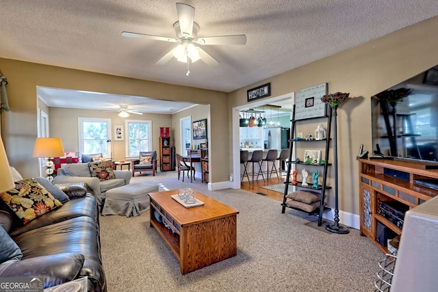 living room featuring ceiling fan, carpet floors, and a textured ceiling