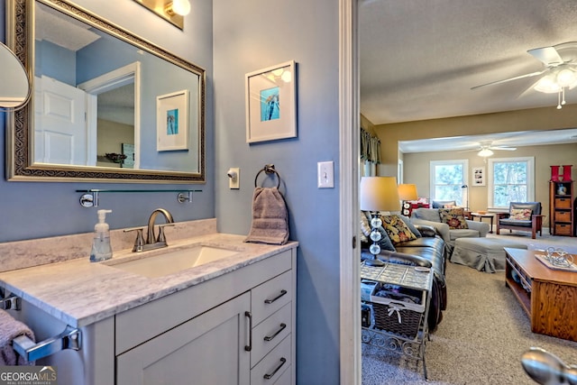 bathroom with ceiling fan, a textured ceiling, and vanity